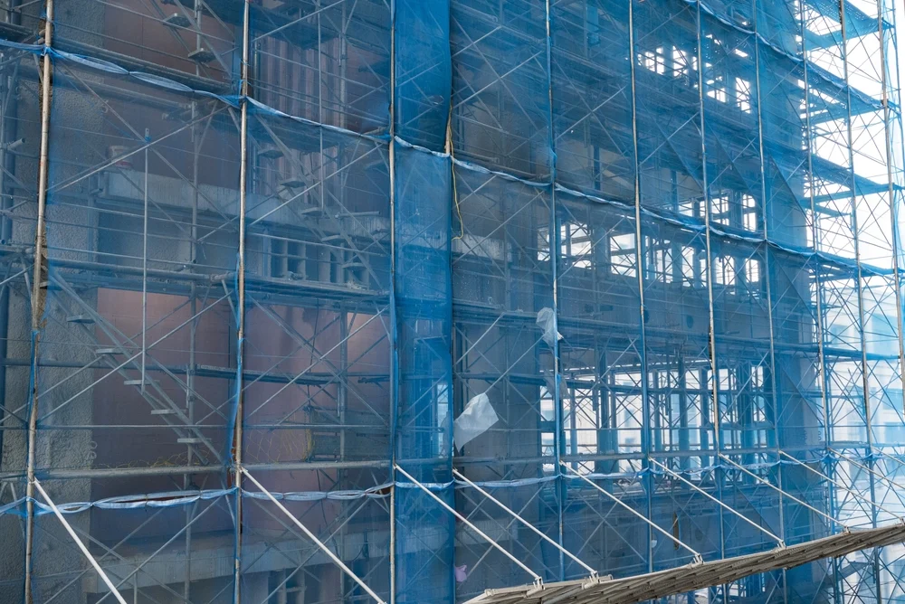 Scaffold on new construction building wrapped in blue safety nets.